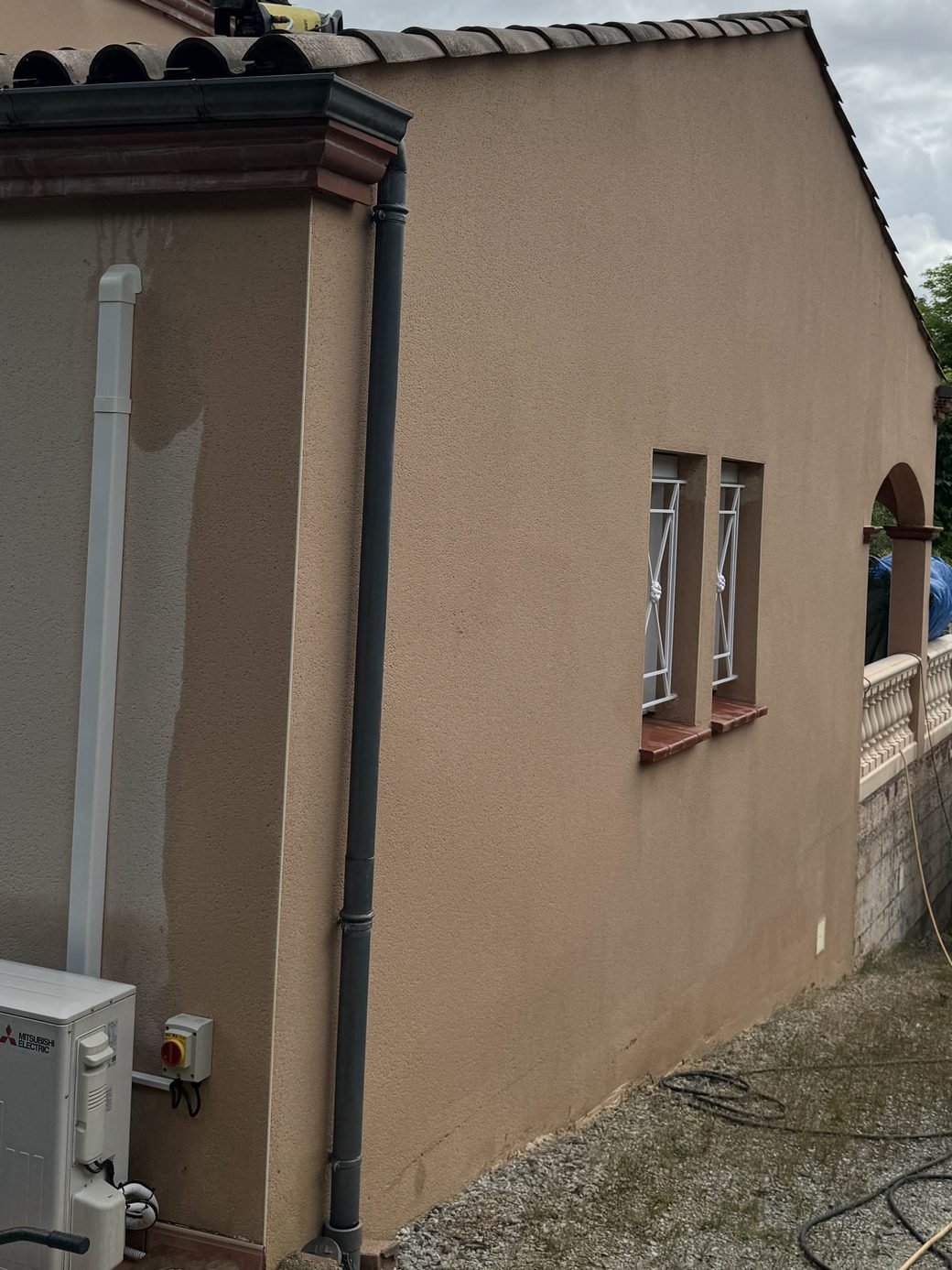 Façade de maison nettoyée, crépi beige uniforme après démoussage à Pompertuzat