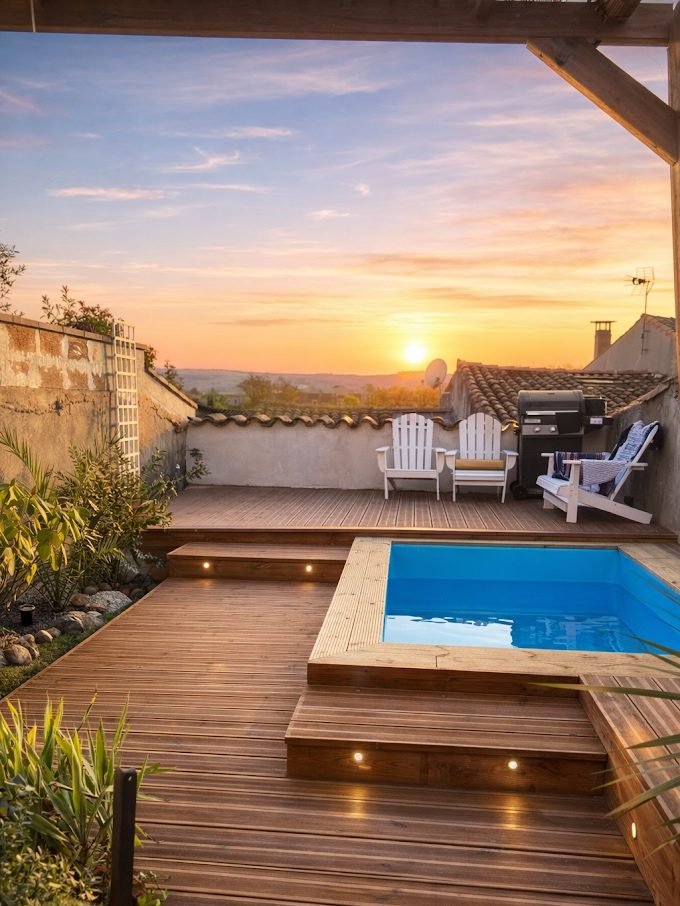 Terrasse en bois avec piscine et éclairage encastré au coucher du soleil, après travaux à Castelnaudary