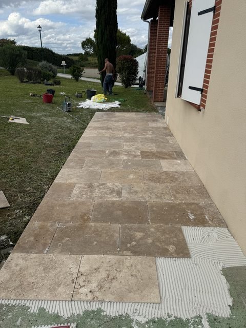Pose de carrelage travertin sur une terrasse extérieure à Bannières