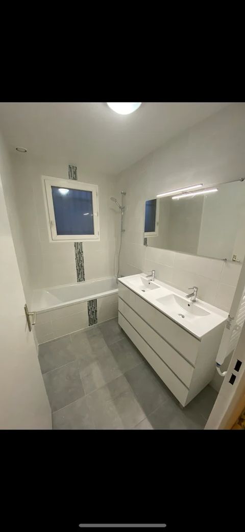 Salle de bain rénovée avec baignoire, double vasque et frise mosaïque